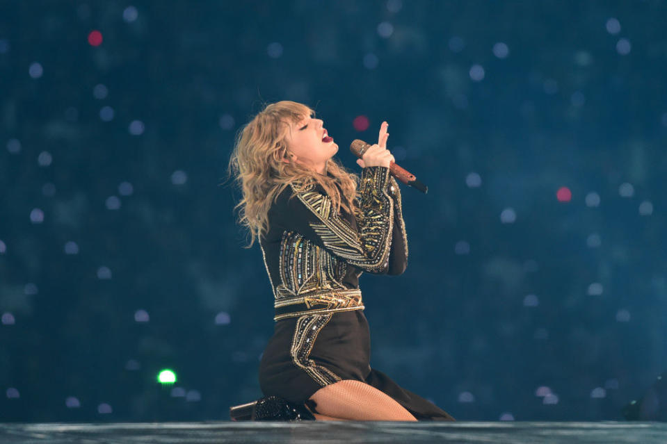 Photo of Taylor Swift in a black and gold dress performing on the reputation tour.