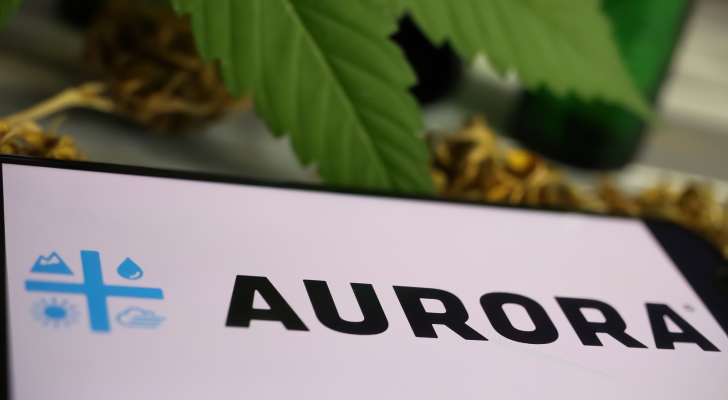 Closeup of mobile phone screen with logo lettering of cannabinoid company Aurora Cannabis (ACB, blurred marijuana leaf (focus on left part of letter R in center)