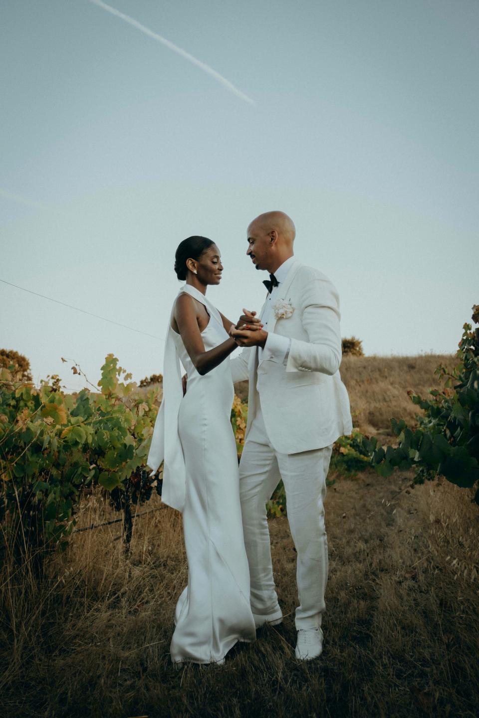 A bride and groom dance as the sun sets over a vineyard on their wedding day.