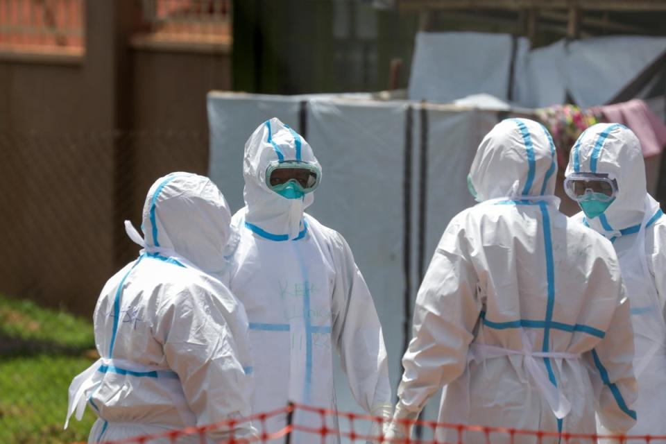 Doctors stand in a circle to say a prayer before entering the Ebola isolation section of Mubende Regional Referral Hospital (AP)