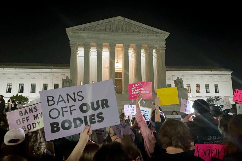 A crowd of people gather outside the Supreme Court, Monday night, May 2, 2022 in Washington.