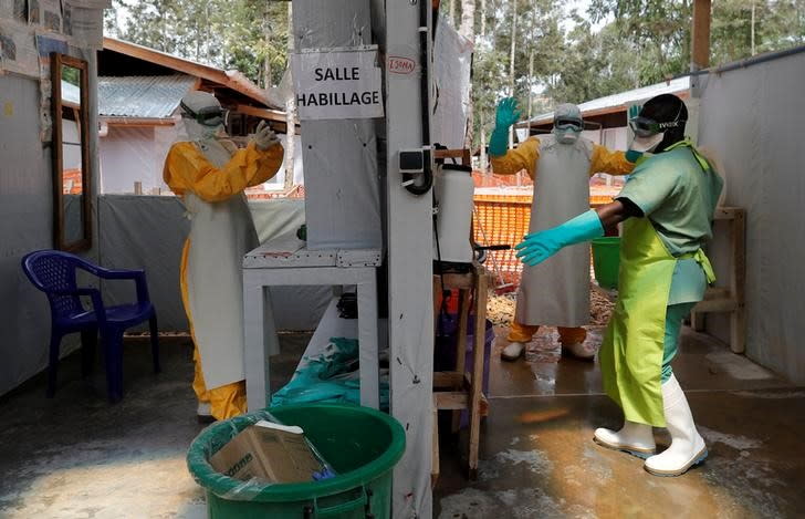 FILE PHOTO: Moise Vaghemi (L), 33, an Ebola survivor who works as a nurse, gets dressed in a protective suit as he prepares to start his shift at an Ebola treatment centre in Katwa