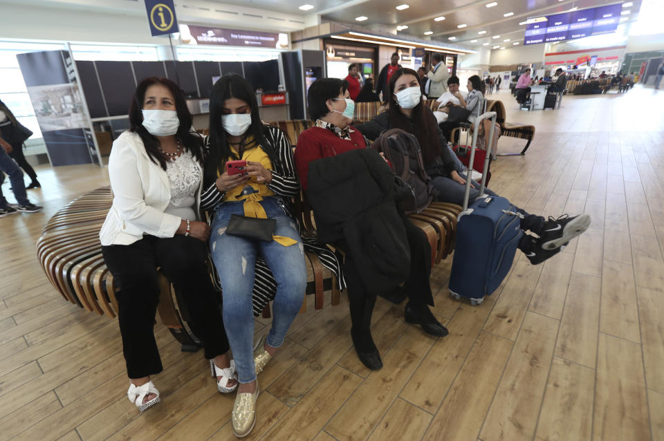 People wearing face masks wearing masks wait for the arrival of their relatives at the Mariscal Sucre International Airport, in Quito, Ecuador, Saturday, Feb. 29, 2020. Officials in Ecuador on Saturday confirmed the first case of the new coronavirus in the South American nation. (AP Photo/Dolores Ochoa)