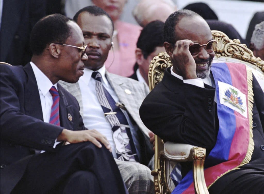 Former Haitian President Jean-Bertrand Aristide, left, jokes with newly sworn-in Haitian President Rene Preval during inauguration ceremonies at the National Palace in Port-au-Prince, Haiti, Feb. 7, 1996. (AP Photo/Daniel Morel, File)