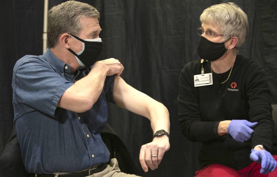 N.C. State Roy Cooper rolls up his sleeve for Carolyn Knaup, RN, as he prepares to receive his COVID-19 vaccination at WakeMed in Raleigh on March 3, 2021.