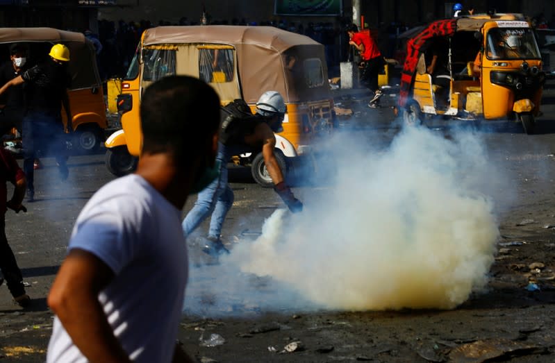 Iraqi demonstrators run away from tear gas thrown by Iraqi security forces during ongoing anti-government protests in Baghdad