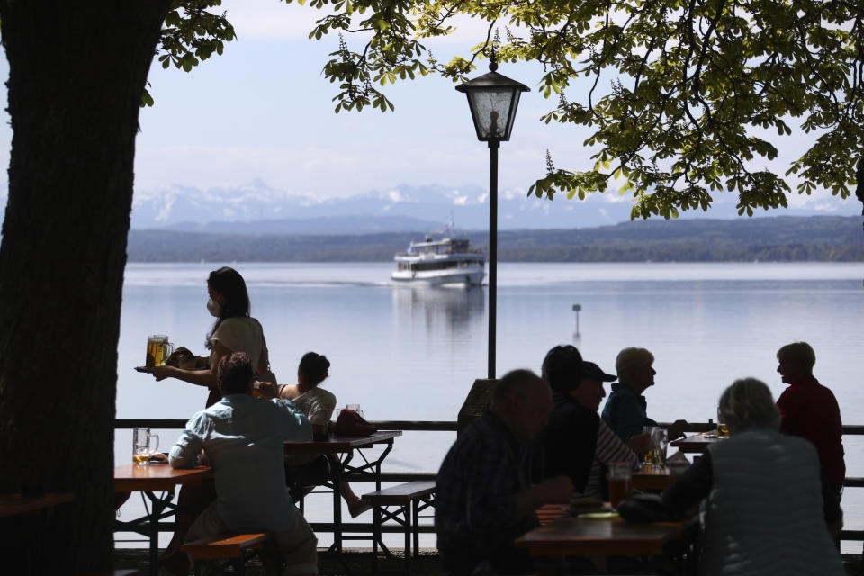 People enjoy the sunny weather and drink beer on the re-opening day of beer gardens, following the lifting of measures to avoid the spread of the corona virus, at lake 'Ammersee' in front of the alps in Inning, Germany, Monday, May 10, 2021. (AP Photo/Matthias Schrader)