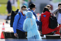 An official in protective suits ensure the temperature of the foreign passengers disembarked from the quarantined Diamond Princess cruise ship before boarding to buses at a port in Yokohama, near Tokyo, Friday, Feb. 21, 2020. Passengers tested negative for COVID-19 started disembarking since Wednesday. (AP Photo/Eugene Hoshiko)