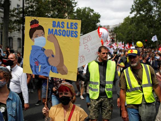 A woman holds a sign saying ‘drop the act’ in a demonstration on the Bastille Day in Paris (REUTERS/Gonzalo Fuentes)