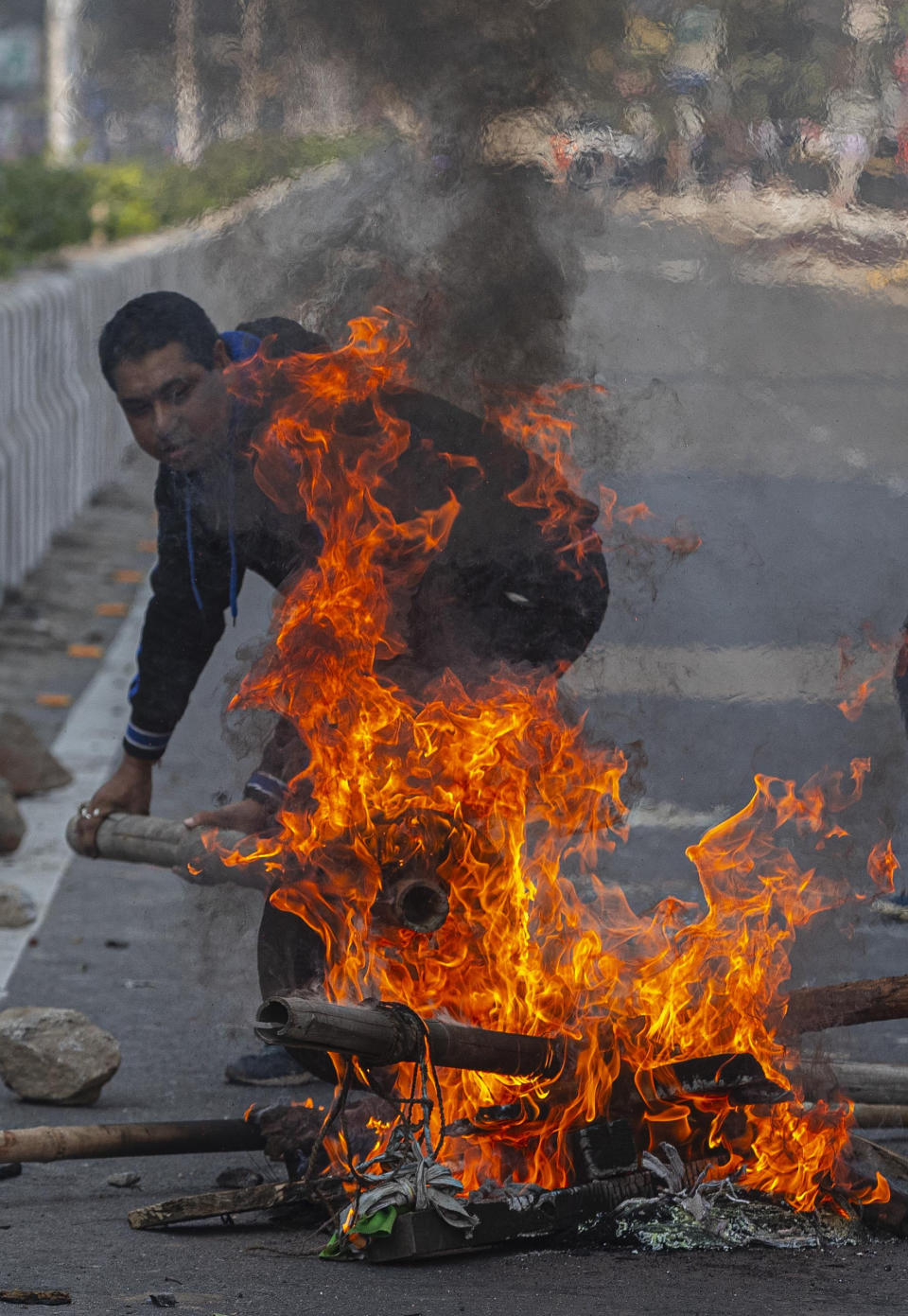 A protestor sets fire to block traffic in Gauhati, India, Thursday, Dec. 12, 2019. Police arrested dozens of people and enforced curfew on Thursday in several districts in India’s northeastern Assam state where thousands protested legislation granting citizenship to non-Muslims who migrated from neighboring countries. (AP Photo/Anupam Nath)