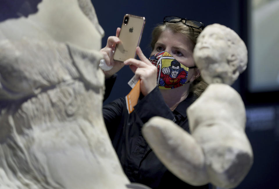 Una mujer toma una fotografía de una escultura en el Pergamonmuseum en Berlín, Alemania el martes 12 de mayo de2020. Tras semanas sin actividad por el coronavirus los museos de Berlín reabrieron el martes. (Foto AP/Michael Sohn)