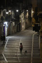 A resident walks with a dog along an empty Curia street, in Pamplona, northern Spain, Saturday, Oct. 24, 2020, as new measures against the coronavirus began in the Navarra province where all bar and restaurants are closed for 15 days from midnight Wednesday. (AP Photo/Alvaro Barrientos)