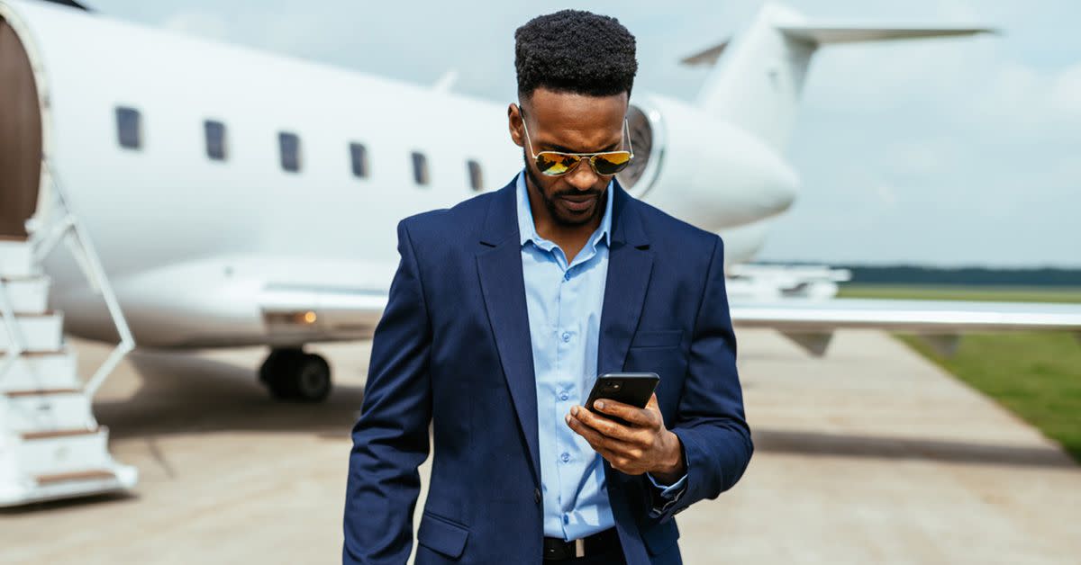 A man who just got off his private plane and is texting on his phone.