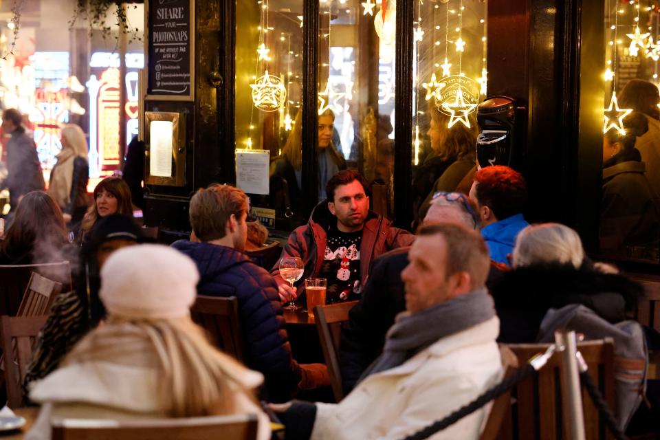 Customers enjoy drinks outside a pub in Covent Garden on the last Saturday for shopping before Christmas, in central London on December 18, 2021. - The British government on Friday reported 93,045 new coronavirus cases, a third consecutive record daily tally, as the Omicron variant fuels a surge in infections across the country. Britain is currently rolling out a mass booster drive in order to vaccinate as many people as possible before the end of the year. (Photo by Tolga Akmen / AFP) (Photo by TOLGA AKMEN/AFP via Getty Images)