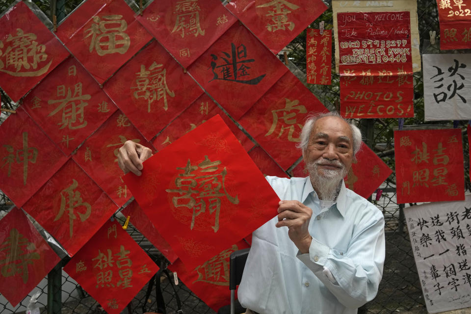 Dereck Kwok, 83-year-old calligraphy artist, shows his "Fai Chun" with Chinese words "Happiness arriving at your Door," traditional decorations with Chinese calligraphy, selling for HK$ 250 each (US $ 32) in Hong Kong on Jan. 26, 2022. In the runup to the Lunar New Year, calligraphers set up on the streets of Hong Kong to write ink-brush phrases on traditional red paper banners for homes and offices. (AP Photo/Kin Cheung)