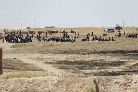 Syrian refugees wait near the border fences as they are pictured from the Turkish side of the border, near Akcakale in Sanliurfa province, Turkey, June 11, 2015. REUTERS/Osman Orsal