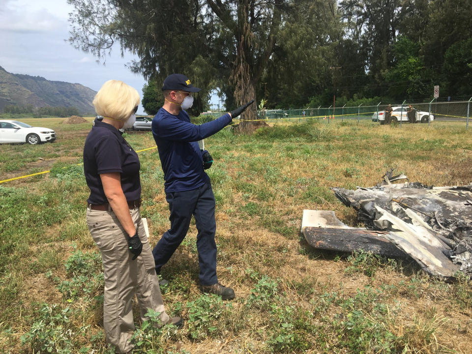 FILE - This June 23, 2019, photo released by the National Transportation Safety Board shows Eliott Simpson, an aviation accident investigator with the NTSB, briefing NTSB board member Jennifer Homendy at the scene of the Hawaii skydiving crash in Oahu, Hawaii. No one aboard survived the crash. The skydiving company that was operating the plane that crashed and killed 11 people last month did not have the proper state permits to take people skydiving. Documents released by the state Wednesday, July 10, 2019, show Oahu Parachute Center was "not in good standing" with the Department of Commerce and Consumer Affairs as of April 2019. It also was not a registered tenant for the state land it occupied. (National Transportation Safety Board via AP)