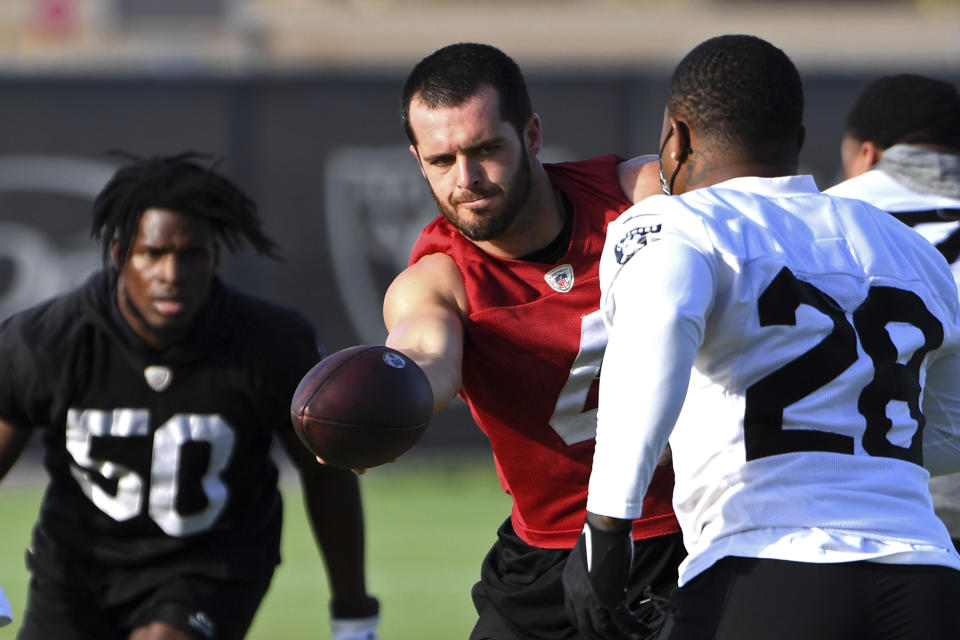 Las Vegas Raiders quarterback Derek Carr (4) hands off the ball torunning back Josh Jacobs (28) during an NFL football practice Wednesday, July 28, 2021, in Henderson, Nev. (AP Photo/David Becker)