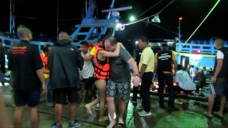 A rescued woman wearing a life jacket hugs a man after a boat capsized off the tourist island of Phuket, Thailand July 5, 2018 in this still image taken from video. Video taken July 5, 2018. REUTERS via Reuters TV