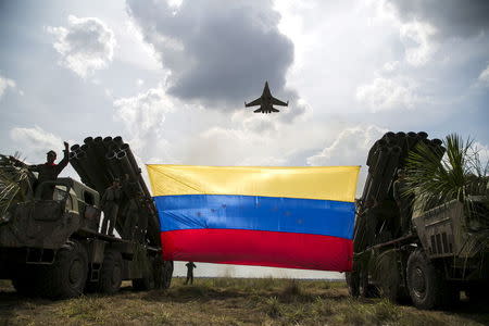 A Russian-made Sukhoi Su-30MKV fighter jet of the Venezuelan Air Force flies over a Venezuelan flag tied to missile launchers, during the "Escudo Soberano 2015" (Sovereign Shield 2015) military exercise in San Carlos del Meta in the state of Apure April 15, 2015. REUTERS/Marco Bello