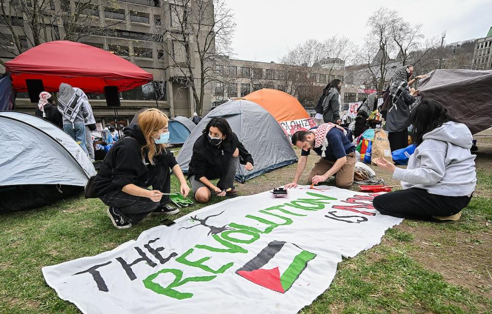 People work on a sign during a pro-Palestinian demonstration at an encampment at McGill University in Montreal, Saturday, April 27, 2024.