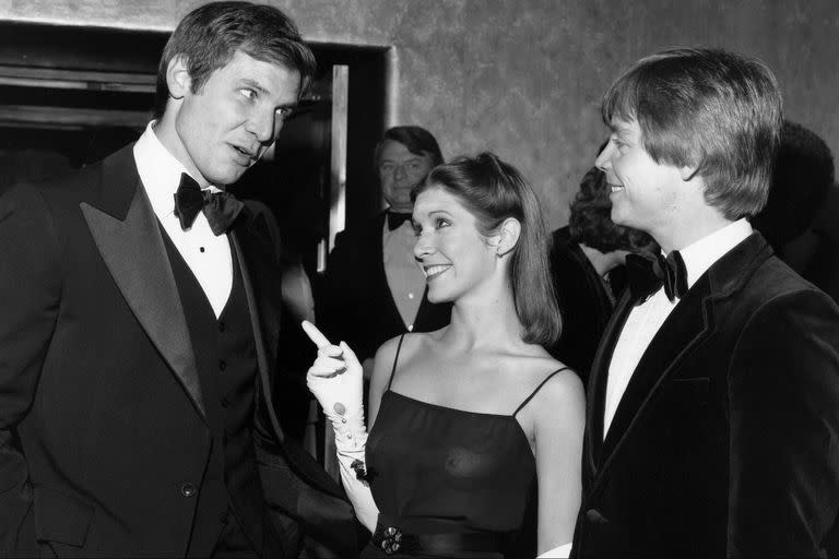 Harrison Ford y Carrie Fisher, intercambiando sonrisas cómplices ante la mirada de Mark Hamill