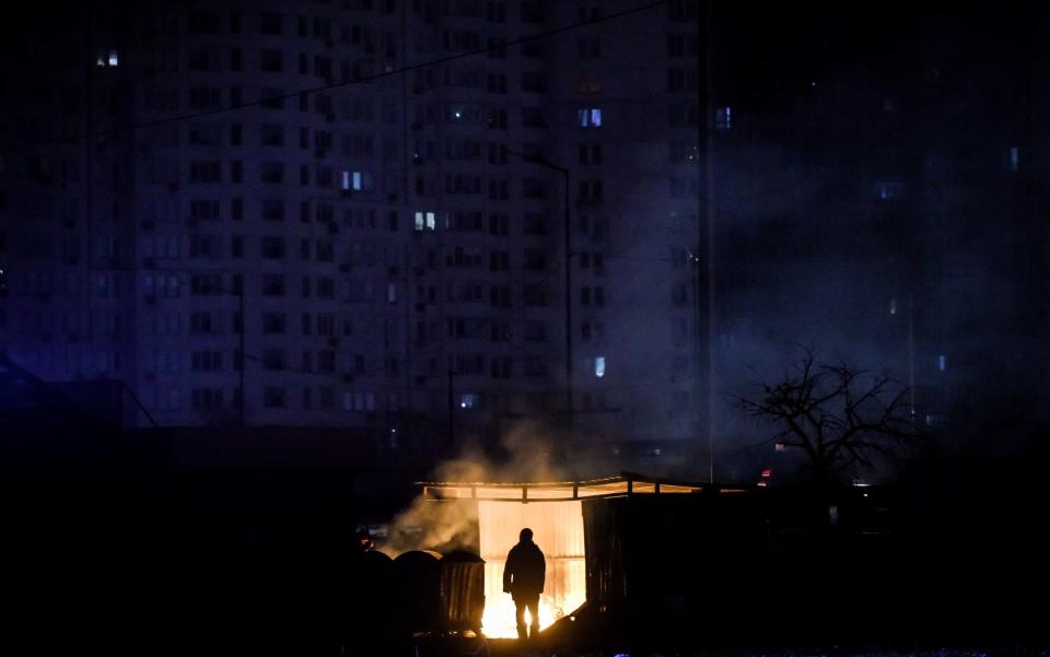 A man stands near burning garbage in front of an apartment building during a scheduled power cut in Kyiv - OLEG PETRASYUK/EPA-EFE/Shutterstock