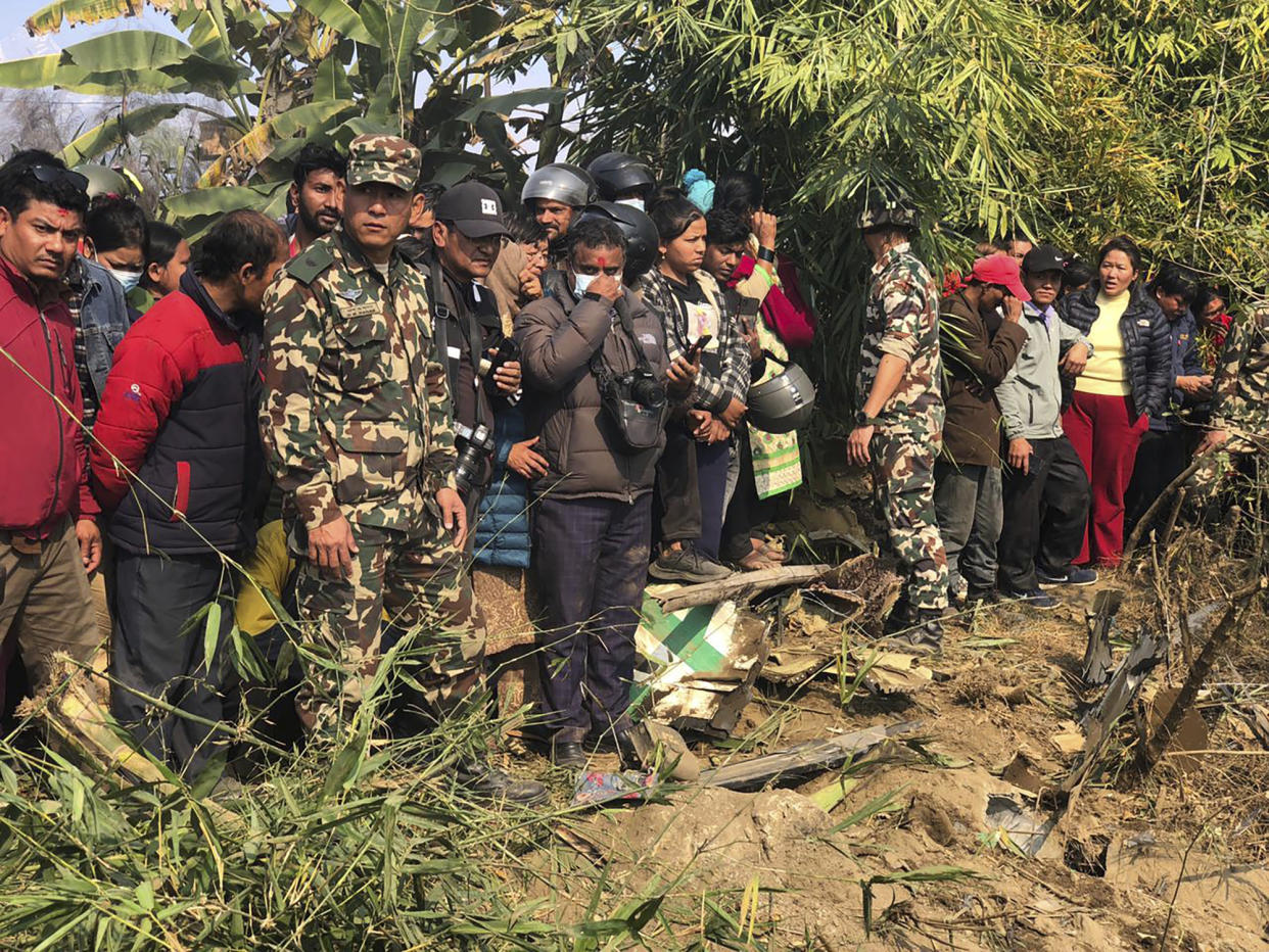 Locals watch the wreckage of a passenger plane in Pokhara, Nepal, Sunday, Jan.15, 2023. A passenger plane with 72 people on board has crashed near Pokhara International Airport in Nepal, the daily newspaper Kathmandu Post reports. The plane was carrying 68 passengers and four crew members. (AP Photo/Ashish Puri)