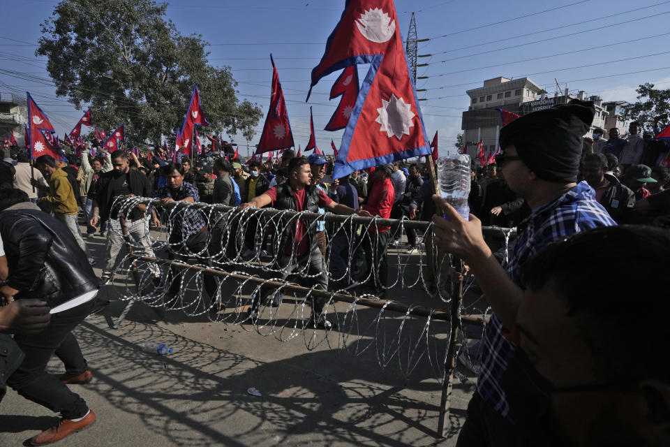 Protesters remove a barbwire fencing during a rally demanding a restoration of Nepal's monarchy in Kathmandu, Nepal, Thursday, Nov. 23, 2023. Riot police used batons and tear gas to halt tens of thousands of supporters of Nepal's former king demanding the restoration of the monarchy and the nation's former status as a Hindu state. Weeks of street protests in 2006 forced then King Gyanendra to abandon his authoritarian rule and introduce democracy. (AP Photo/Niranjan Shrestha)