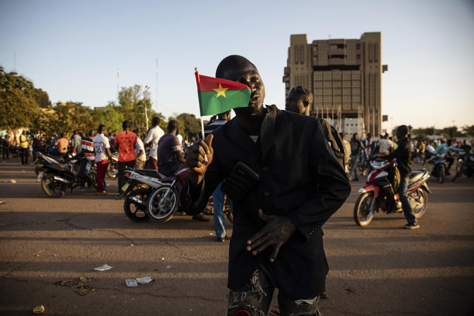 A Save Burkina Faso movement supporter holds a Burkina Faso flag after it was announced that Lt. Col. Paul Henri Sandaogo Damiba has taken the reins of the country in Ouagadougou Monday Jan. 24, 2022. More than a dozen mutinous soldiers declared Monday on state television that a military junta now controls Burkina Faso after they detained the democratically elected president following a day of gun battles in the capital. (AP Photo/Sophie Garcia)