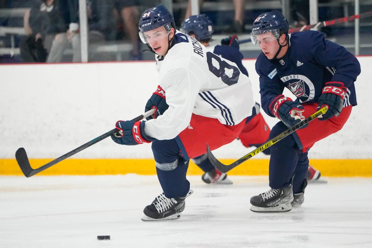 Blue Jackets defenseman Guillaume Richard (left) and forward Jordan Dumais eye the puck during development camp July 13.