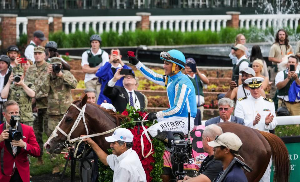 Jockey Javier Castellano holds a rose as he and Mage walk to the Winner's Circle after winning the 149th Kentucky Derby Saturday.