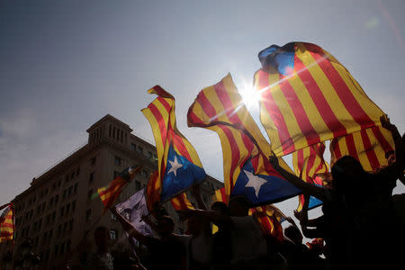 People hold on to Catalan separatist flags on top of an air vent during a demonstration two days after the banned independence referendum in Barcelona, Spain, October 3, 2017. REUTERS/Enrique Calvo