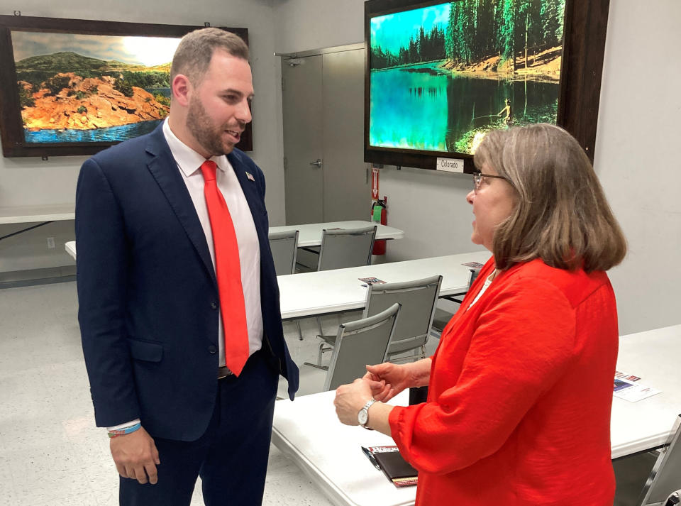 FILE- Republican U.S. Senate candidate Jackson Lahmeyer, a Tulsa-area pastor, speaks to Edmond resident Winona Heltzel on March 15, 2022, at the H&H Shooting Sports gun range during a meeting of the Oklahoma 2nd Amendment Association in Oklahoma City. The pro-firearms association was little-known a decade ago but has grown into a formidable political player at the state Capitol. (AP Photo by Sean Murphy_File)