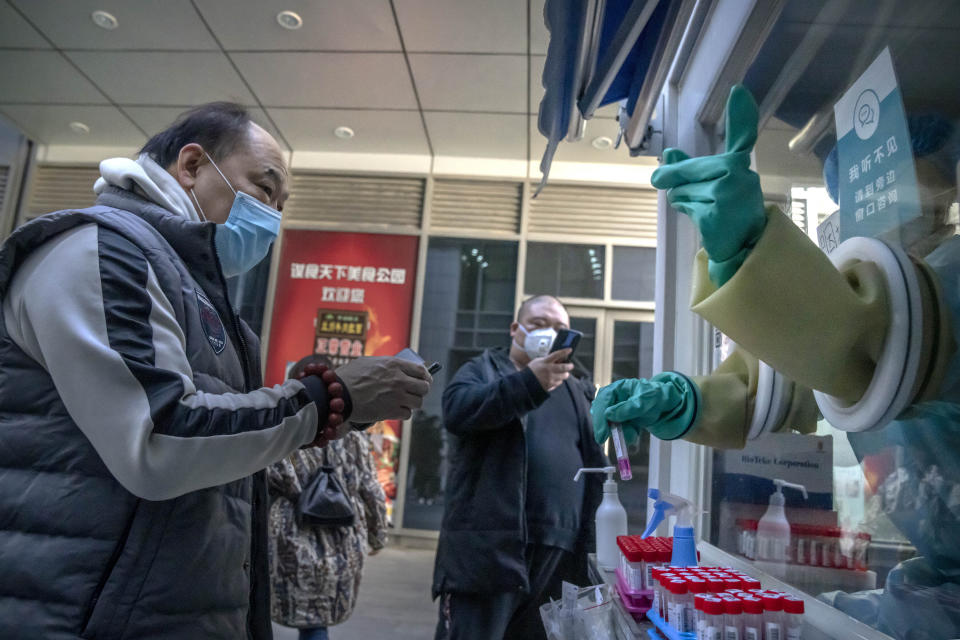 A man gets instructions from a worker inside a mobile coronavirus testing facility at an office complex in Beijing, Wednesday, Dec. 1, 2021. Although China has so far largely controlled the spread of COVID-19 in recent months, a negative coronavirus test is often required for domestic travel or to attend some events. (AP Photo/Mark Schiefelbein)