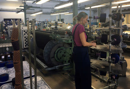 FILE PHOTO: A worker positions bobbins of yarn onto a machine at the Reda wool mill factory in Valle Mosso near Biella, northern Italy, December 1, 2016. Picture taken December 1, 2016. REUTERS/Giulia Segreti/File Photo