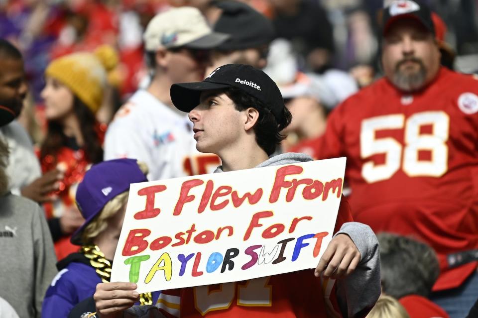 A Taylor Swift fan holds a sign in the stands of the Chiefs-Minnesota Vikings game on Oct. 8, 2023. The game was held in Minneapolis, more than a thousand miles from Boston. <a href="https://www.gettyimages.com/detail/news-photo/kansas-city-chiefs-fan-holds-up-a-sign-in-reference-to-news-photo/1724636637" rel="nofollow noopener" target="_blank" data-ylk="slk:Stephen Maturen/Getty Images;elm:context_link;itc:0;sec:content-canvas" class="link ">Stephen Maturen/Getty Images</a>