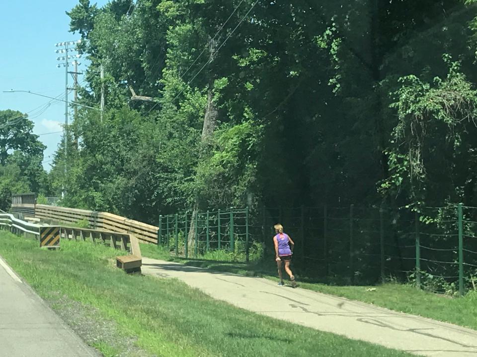 A woman runs the Lansing River Trail Monday, July 15, 2019 by the Red Cedar Natural Area where a man who was impaled on a stump after a fall from a tree was rescued Saturday.