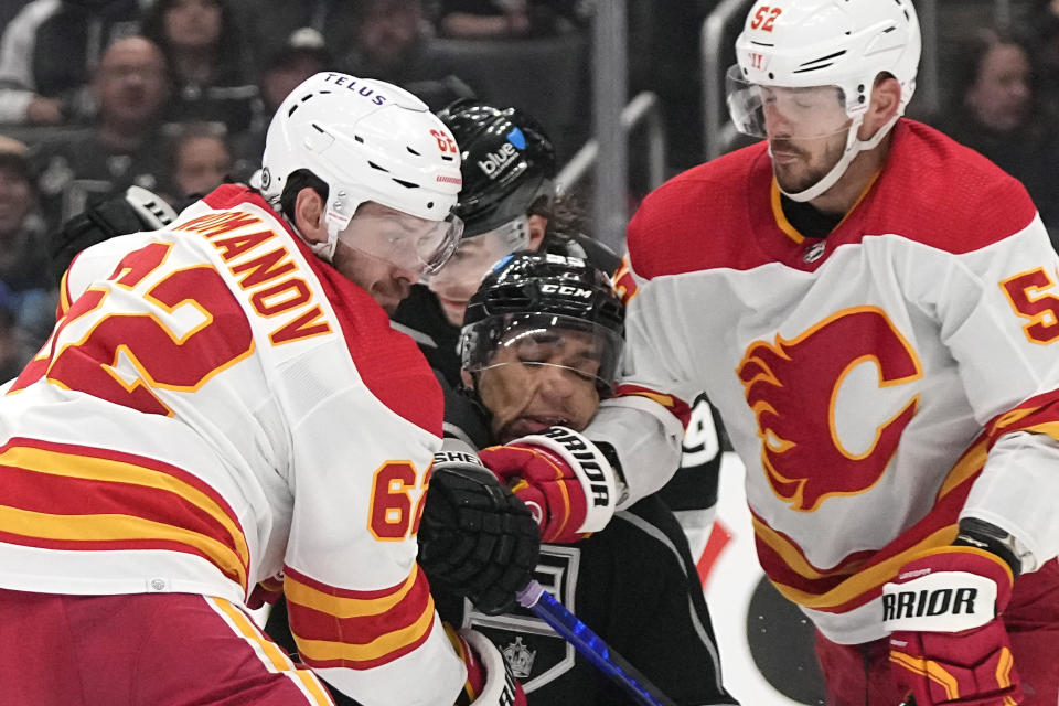 Los Angeles Kings right wing Quinton Byfield, center, gets sandwiched between Calgary Flames defenseman Daniil Miromanov, left, and defenseman MacKenzie Weegar as they battle for the puck during the second period of an NHL hockey game Thursday, April 11, 2024, in Los Angeles. (AP Photo/Mark J. Terrill)