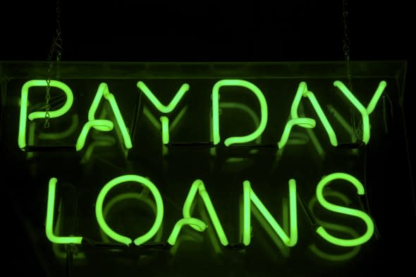 Payday Loans sign glows in green neon on a black background