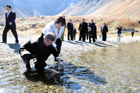 South Korean President Moon Jae-in with his wife first lady Kim Jung-sook standing next to him, fills a plastic bottle with water from the Heaven lake of Mt. Paektu, North Korea, September 20, 2018. Pyeongyang Press Corps/Pool via REUTERS