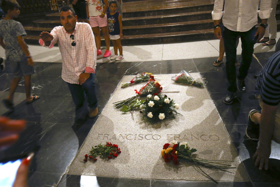 A man salutes as he stands next to the tomb of former Spanish dictator Francisco Franco inside the basilica at the the Valley of the Fallen monument near El Escorial, outside Madrid on Friday, Aug. 24, 2018. Spain's center-left government has approved legal amendments that it says will ensure the remains of former dictator Gen. Francisco Franco can soon be dug up and removed from a controversial mausoleum. (AP Photo/Andrea Comas)