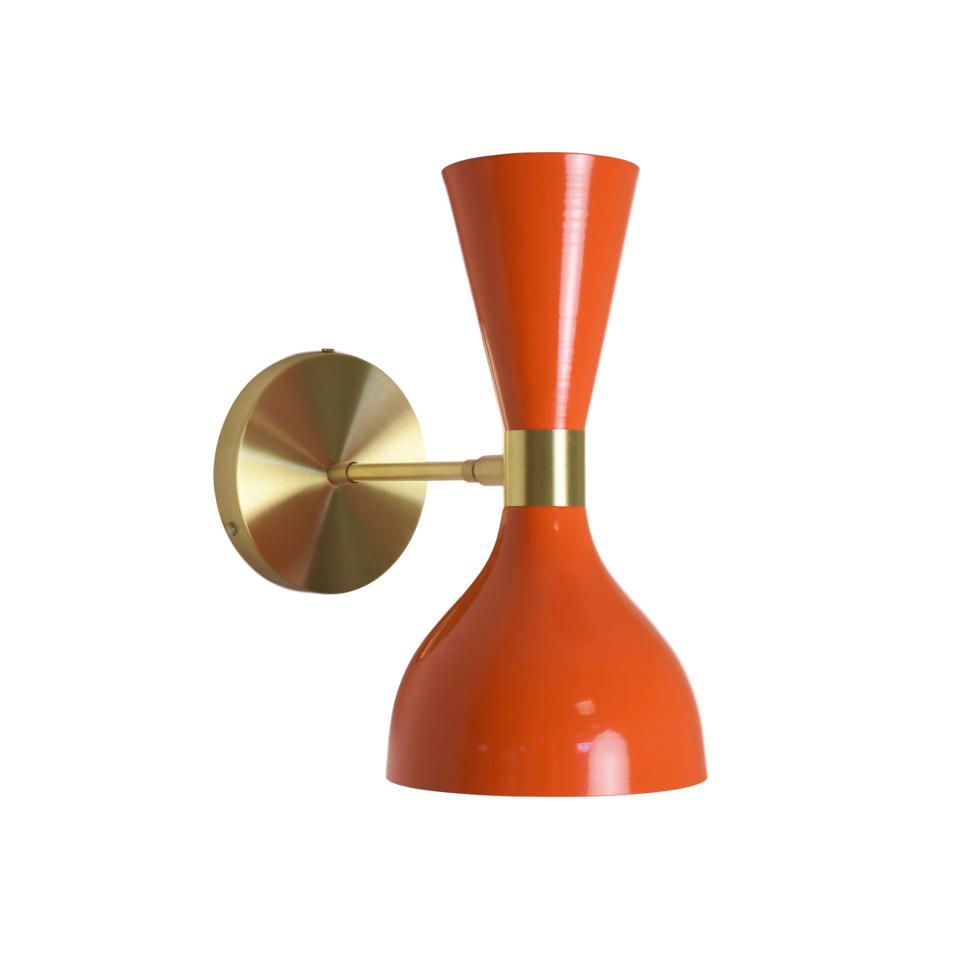 This undated photo shows Blueprint Lighting's Ludo wall sconce. The shape of a wine glass inspired the sconce in tangerine is shown here. The fixture's terracotta-hued enameled finish contrasts nicely with the articulating brass arm. Terracotta blends well with many metal tones and finishes. (Blueprint Lighting via AP)