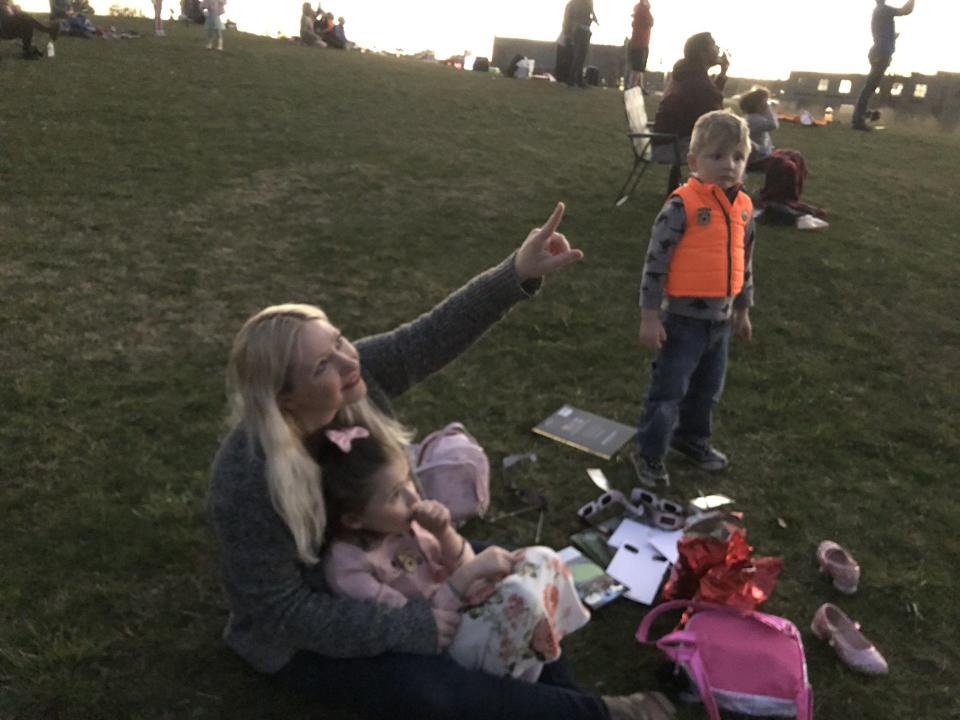 Ashley Finnie, of Lee Center, and her kids Harlie, 7, and James, 5, watch as the moon slowly covers the sun at Fort Stanwix National Monument on April 8, 2024.