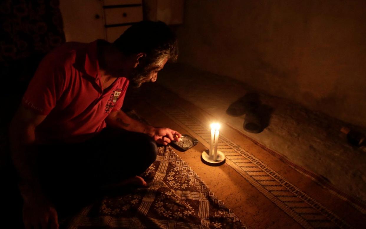 A Lebanese man smokes a cigarette by candlelight in the capital Beirut on July 10, 2021 - ANWAR AMRO/AFP