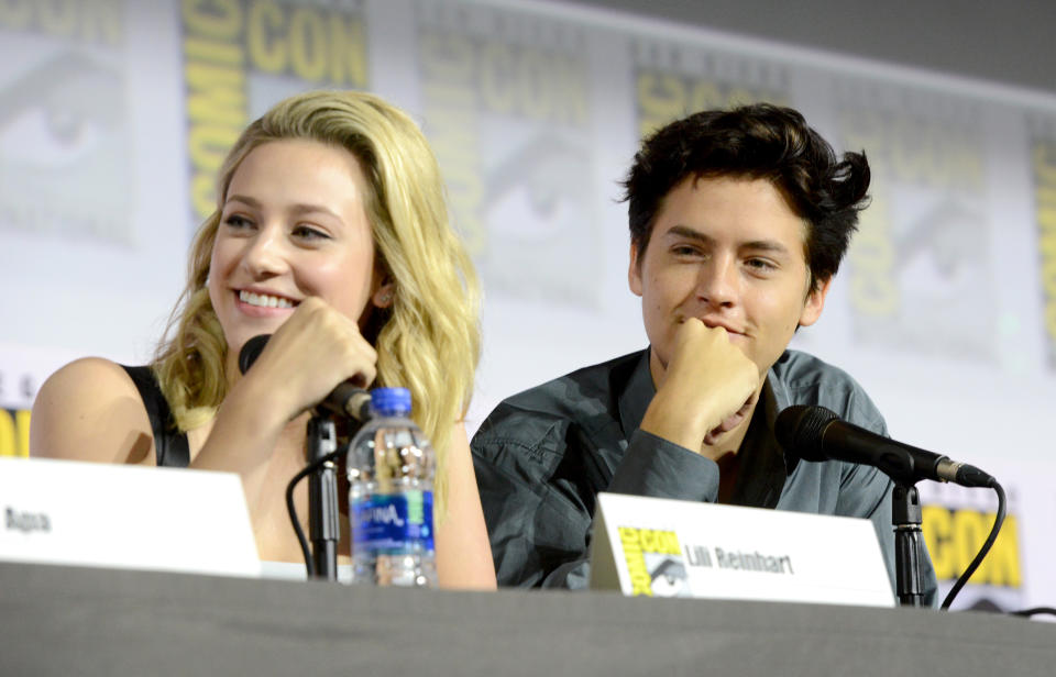 Lili Reinhart and Cole Sprouse smiling during a Comic-Con panel