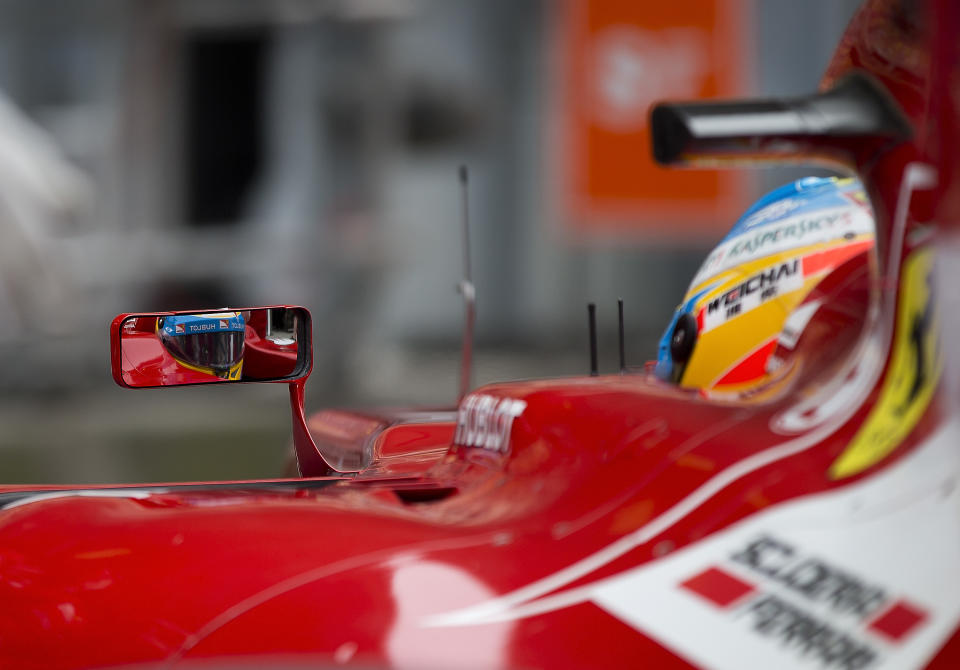 Ferrari driver Fernando Alonso of Spain is reflected on his car side mirror as he return to his garage during the practice session ahead of Sunday's Chinese Formula One Grand Prix at Shanghai International Circuit in Shanghai, China Friday, April 18, 2014. (AP Photo/Andy Wong)