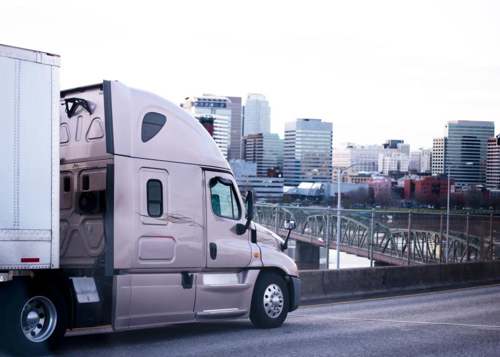 A big rig parked by a bridge in a city.