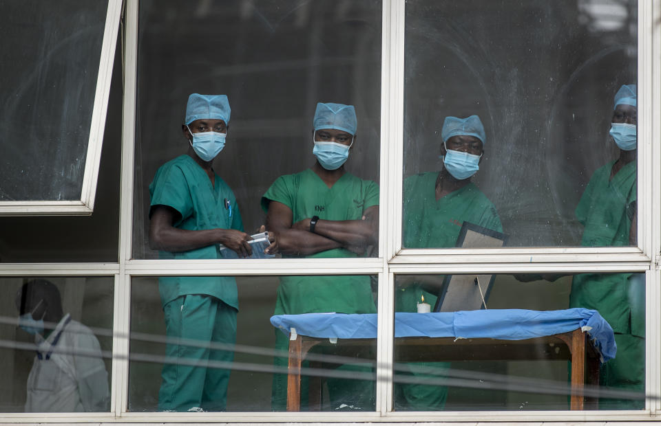 FILE - In this March 5, 2021, file photo, medical staff look out from a window as officials prepare for a ceremony to commence the country's first coronavirus vaccinations using AstraZeneca COVID-19 vaccine provided through the global COVAX initiative, at Kenyatta National Hospital in Nairobi, Kenya. The suspension of the AstraZeneca vaccine in several European countries could fuel skepticism about the shot far beyond their shores, potentially threatening the rollout of a vaccine that is key to the global strategy to stamp out the coronavirus pandemic, especially in developing nations. (AP Photo/Ben Curtis, File)