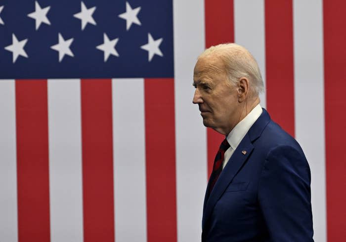 Profile view of Joe Biden in a suit before an American flag